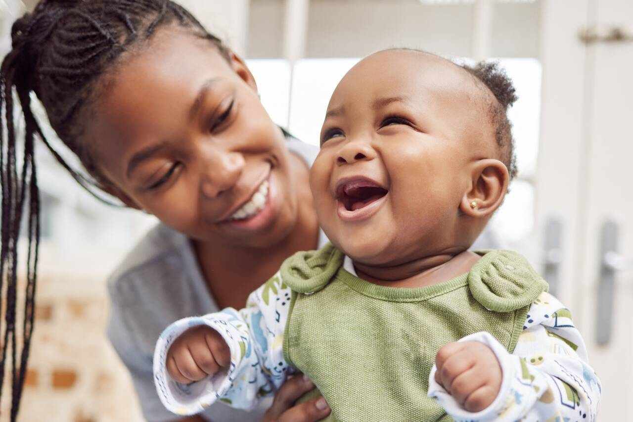Mãe sorrindo com seu bebê feliz em casa