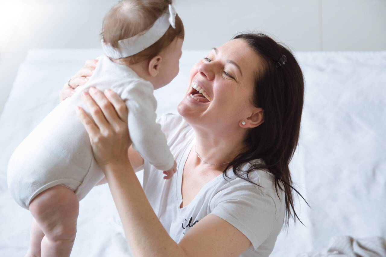 Mãe sorrindo enquanto segura o bebê nos braços