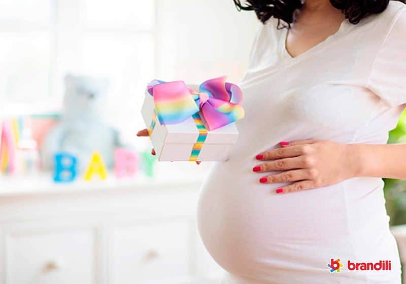 mamãe grávida com a mão na barriga segurando um presente