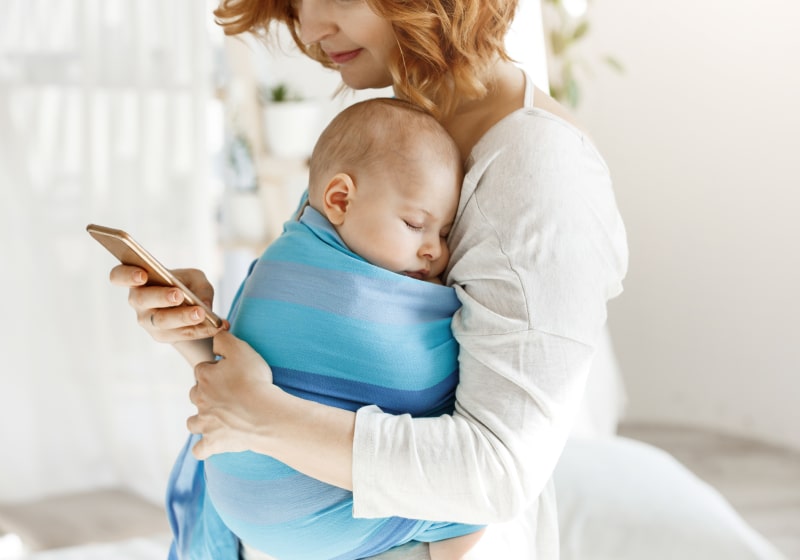 imagem de mulher com bebe no colo e mexendo no celular 