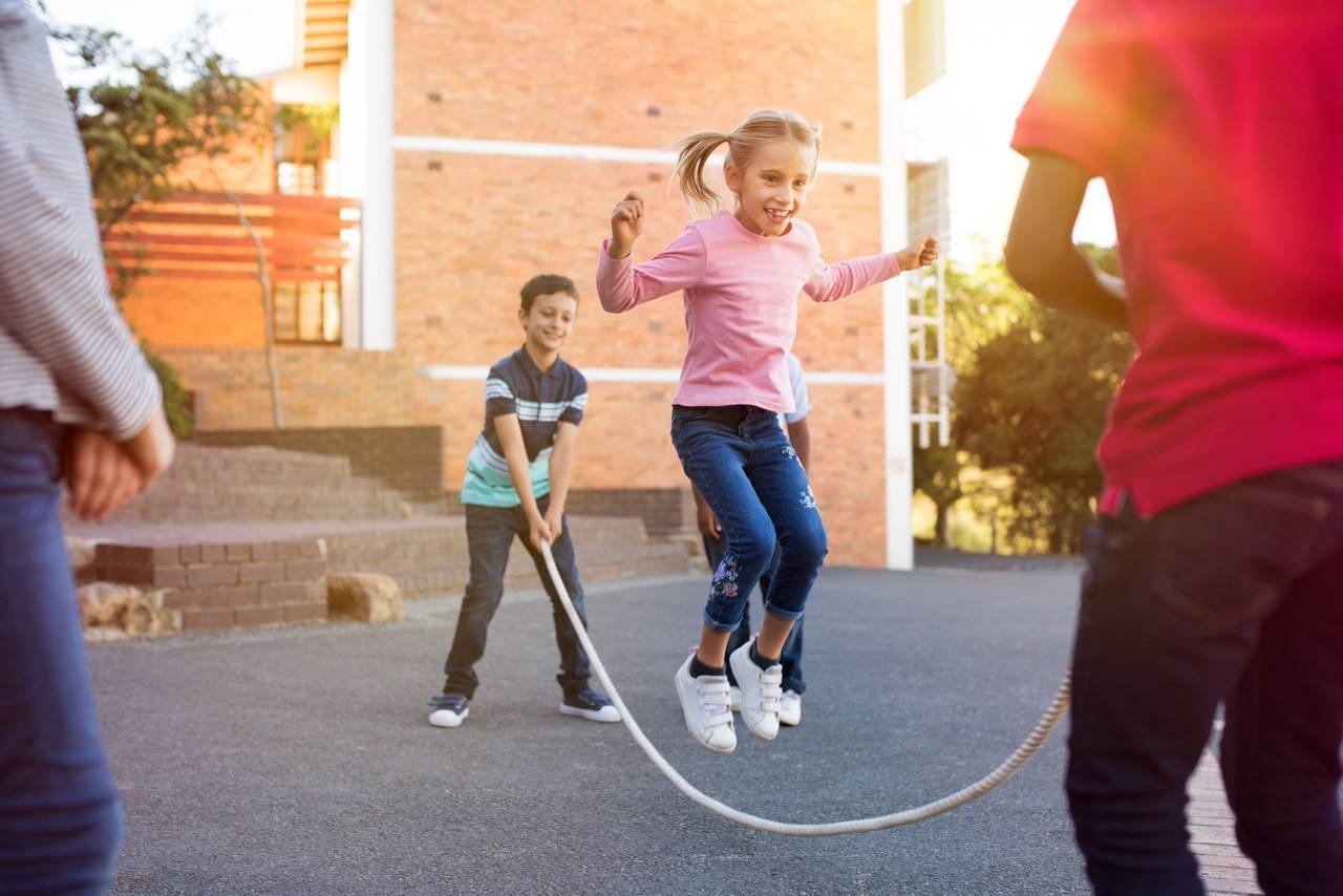 crianças em um pátio brincando de pular corda