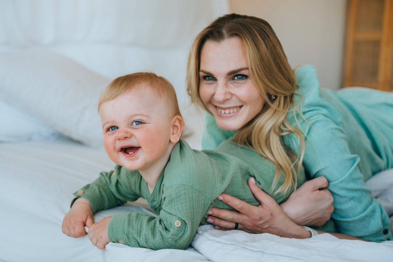 mãe deitada na cama com um bebê cuidando para ele não pegar bronquite