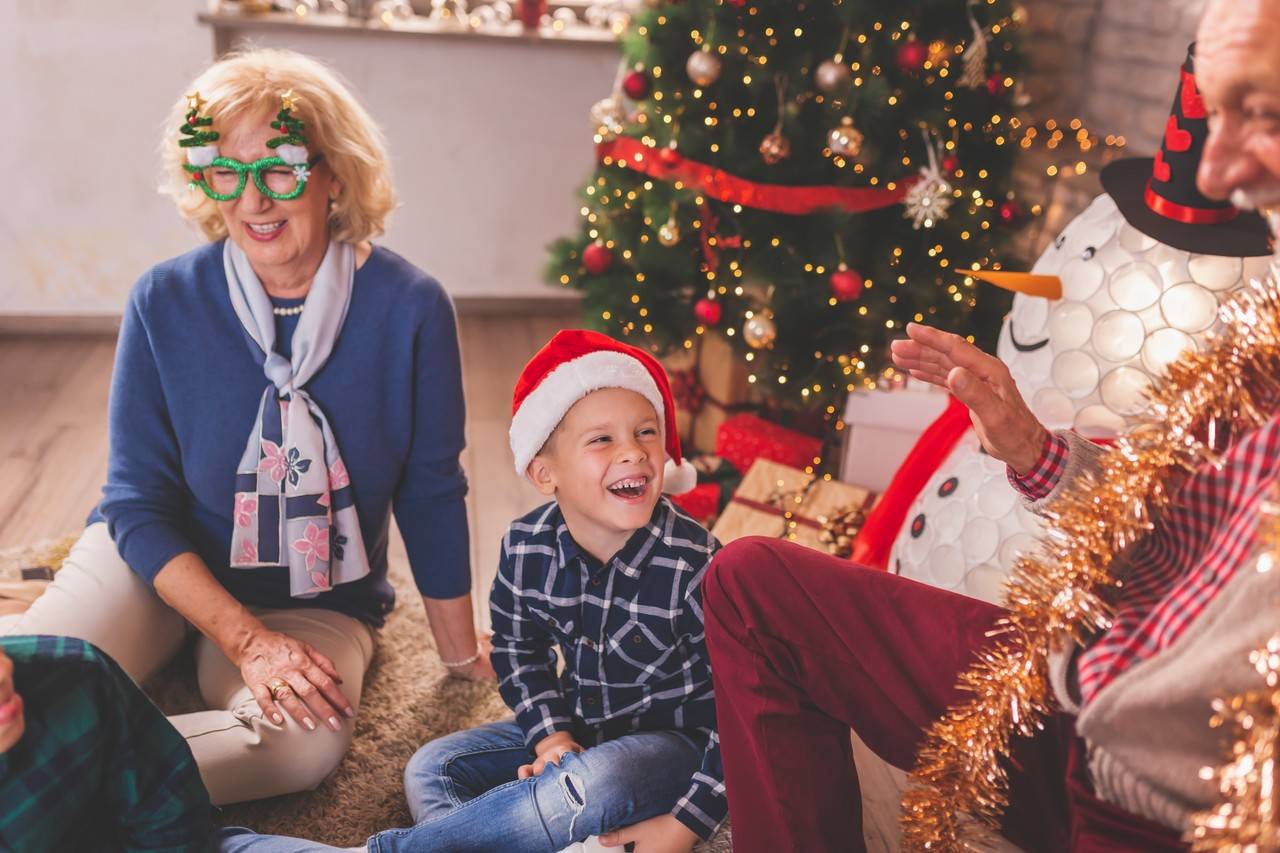 vovôs sentados com o neto ao lado da árvore de natal