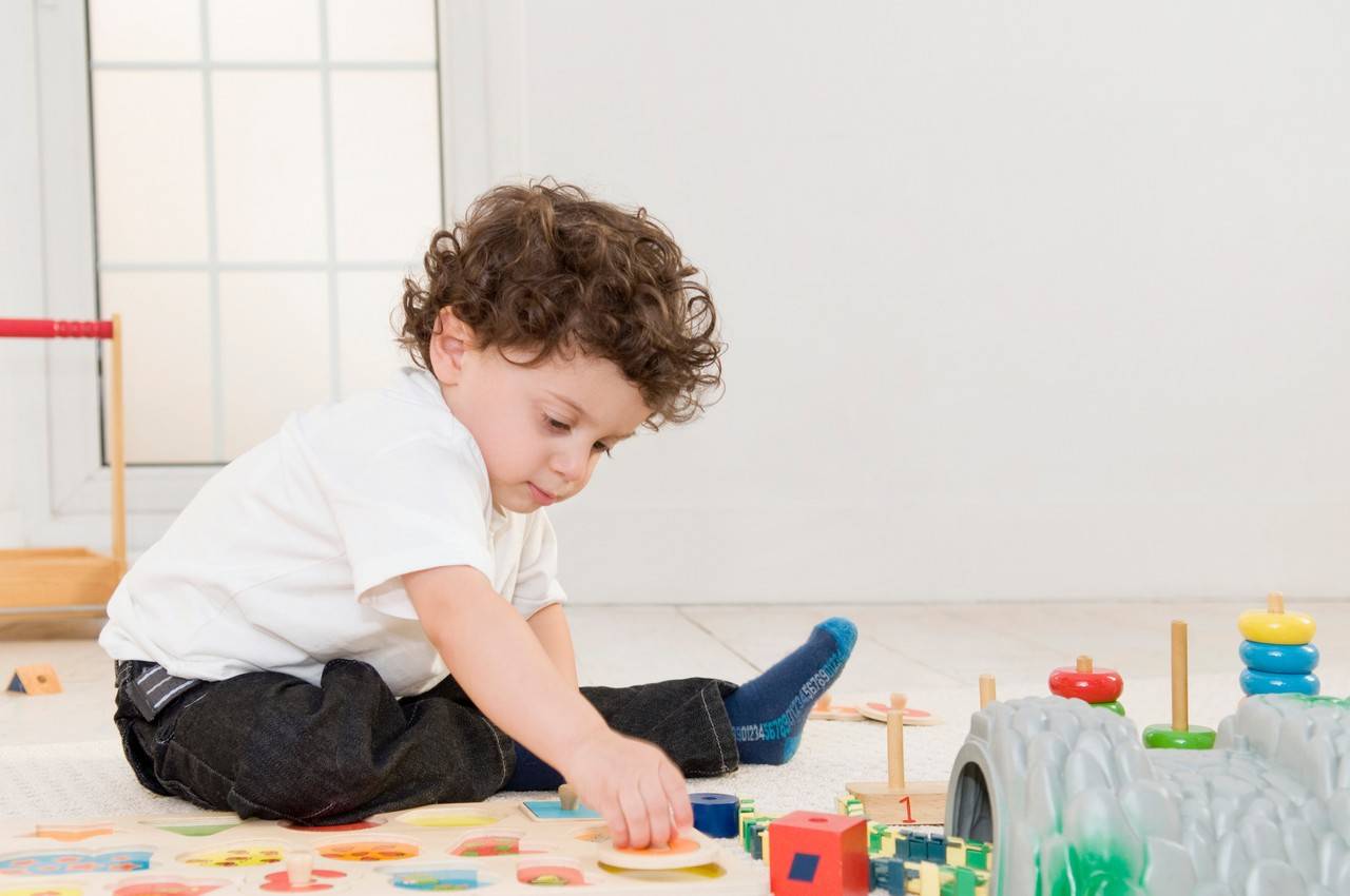 menininho de dois anos brincando com objetos sensoriais e blocos de montar