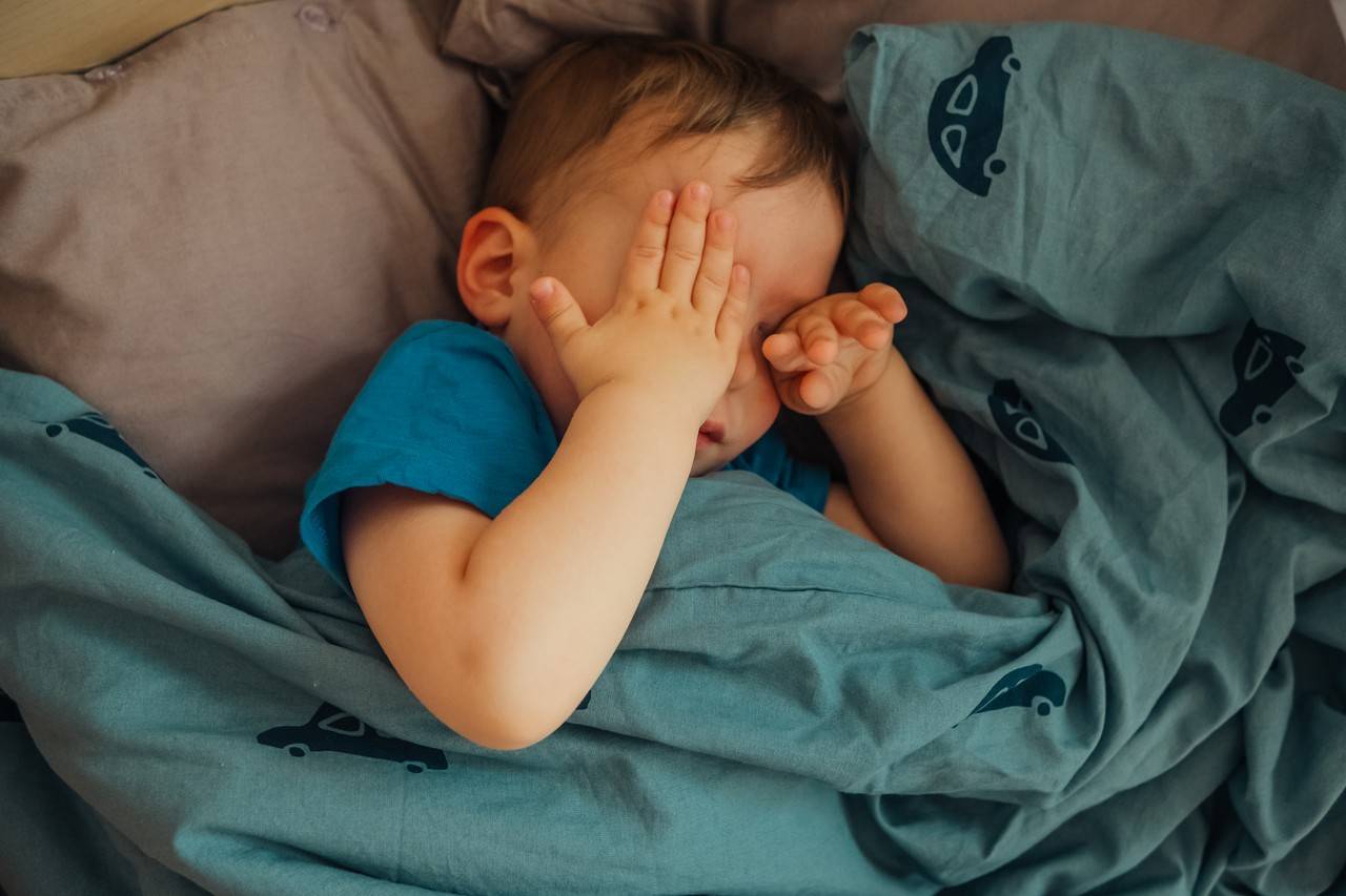 menino de dois anos deitado na cama despreguiçando