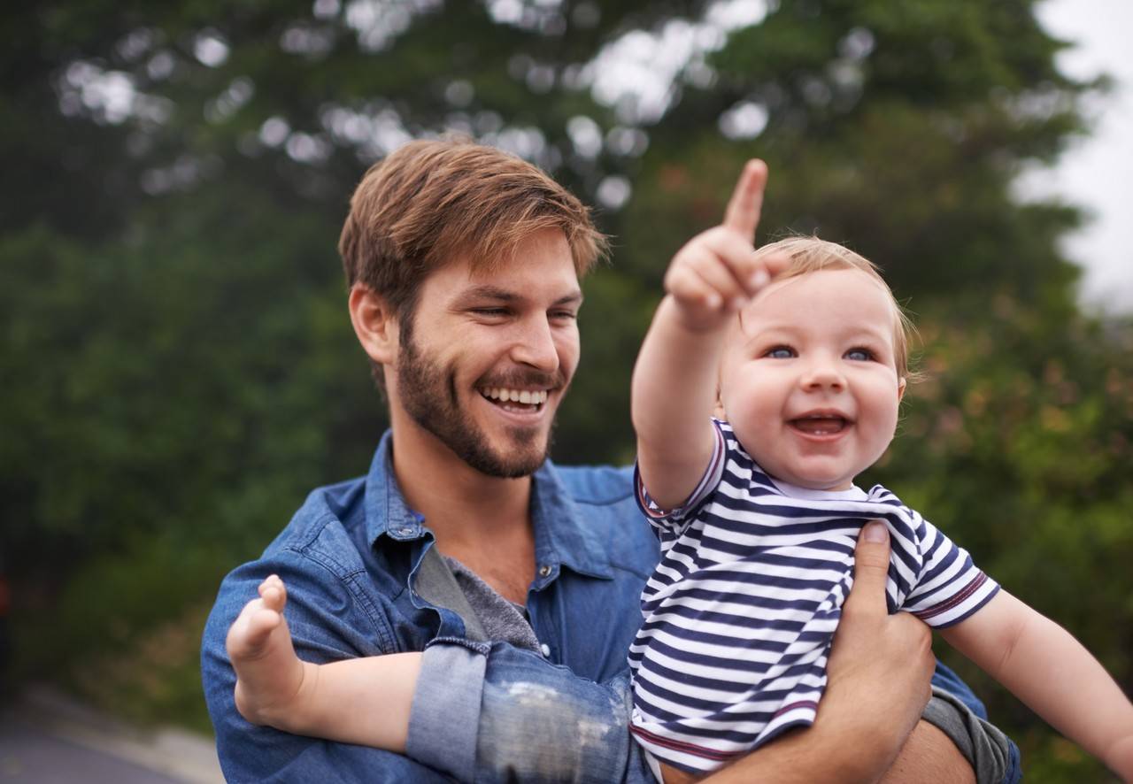 pai com filho no colo apontando para cima