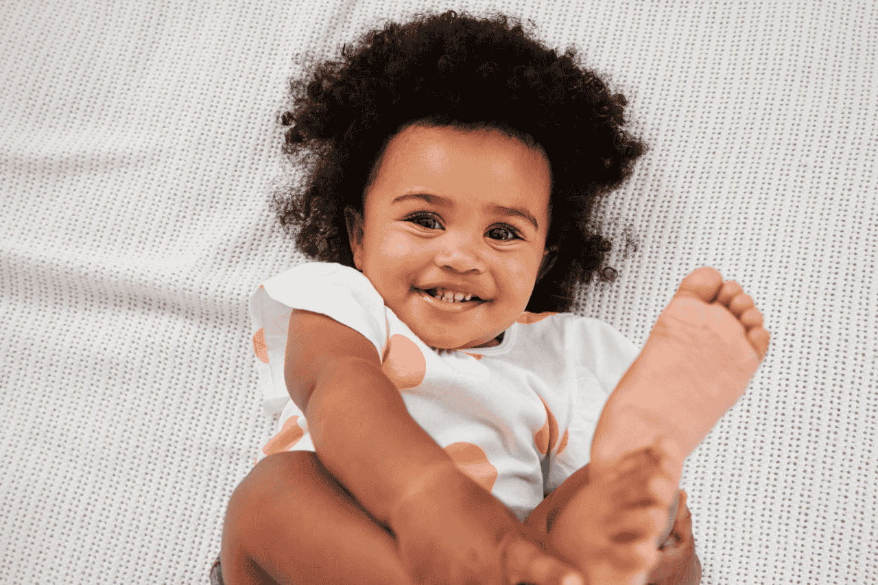 bebê segurando o pé sorrindo