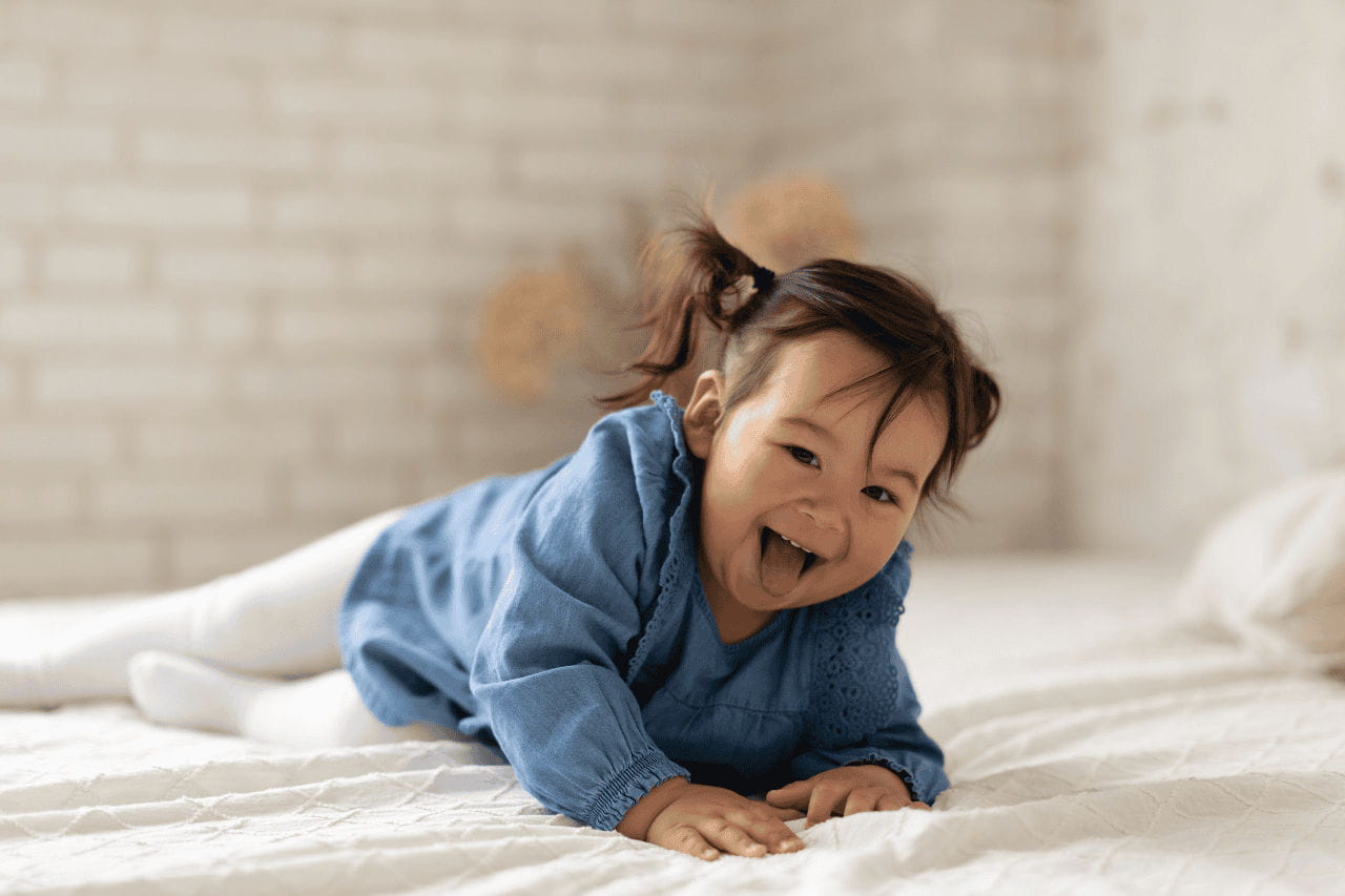 bebê japonesa sorrindo na cama