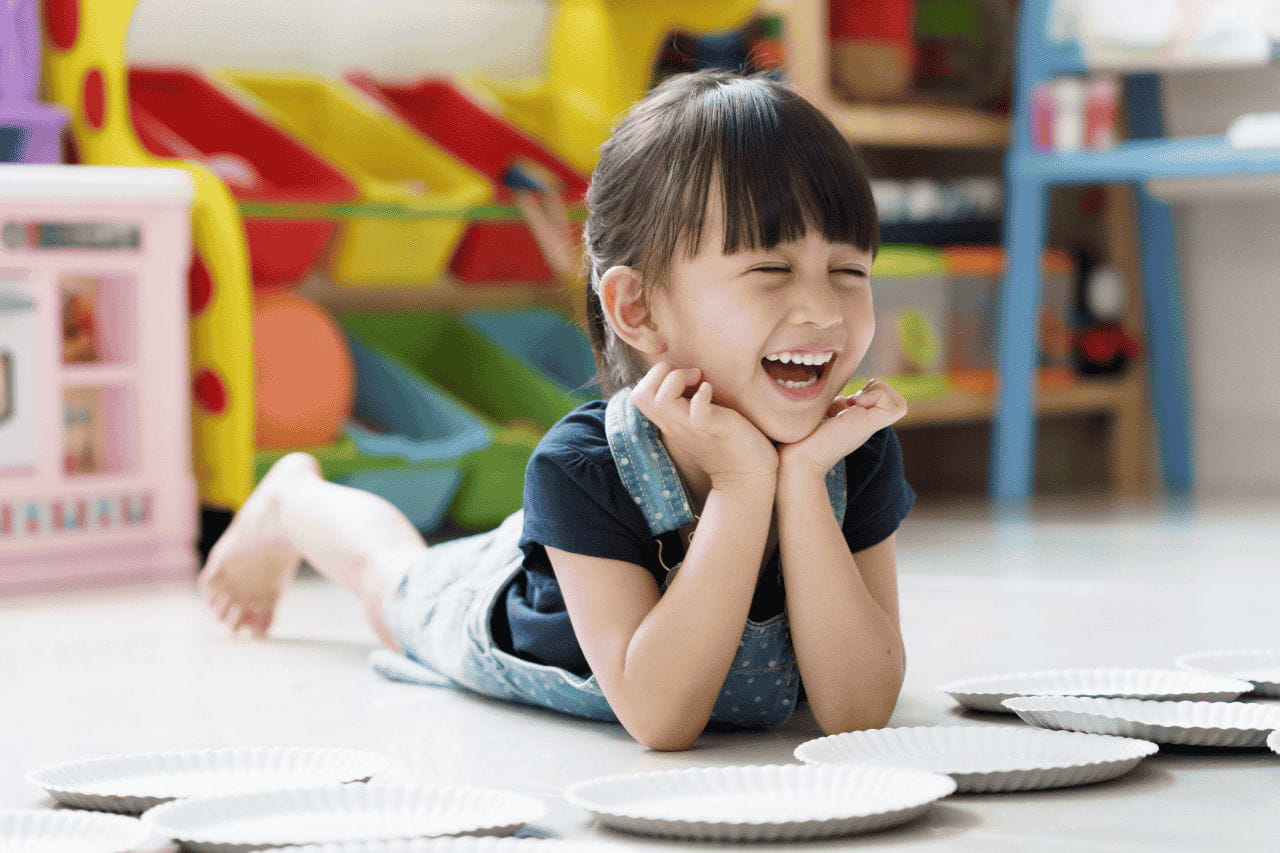 menina sorrindo apoiando braço no chão