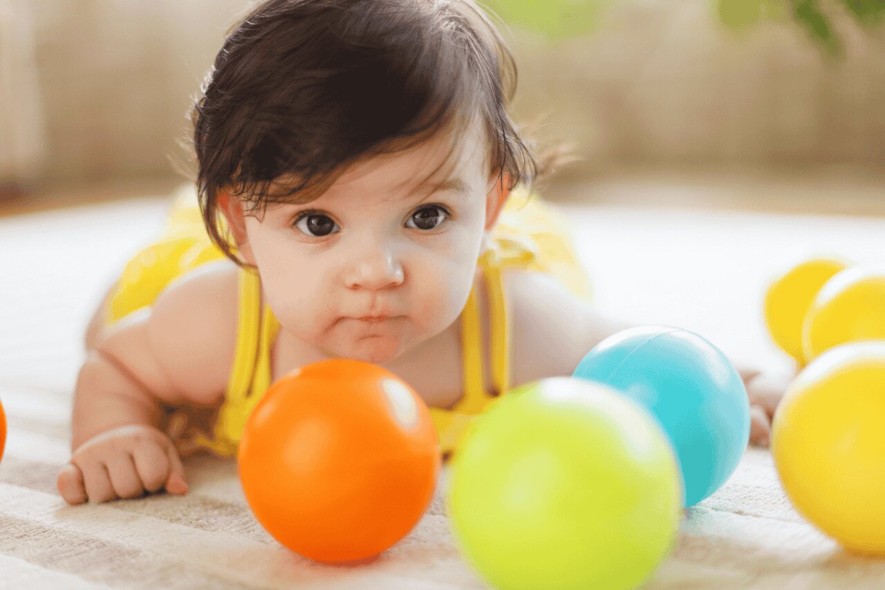 Bebê brincando com bolas coloridas no chão