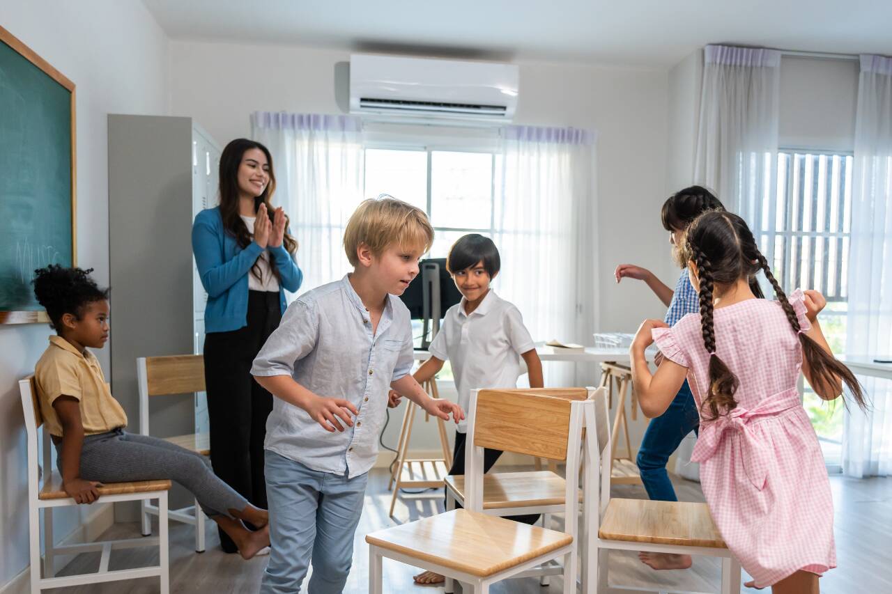 Crianças brincando em sala de aula com professora.