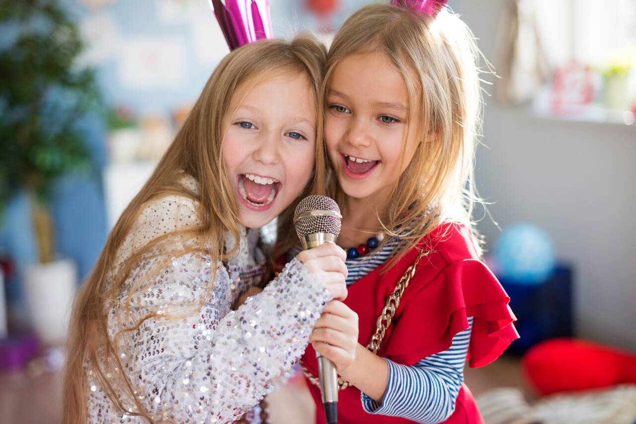 Duas crianças cantando felizes com microfone.