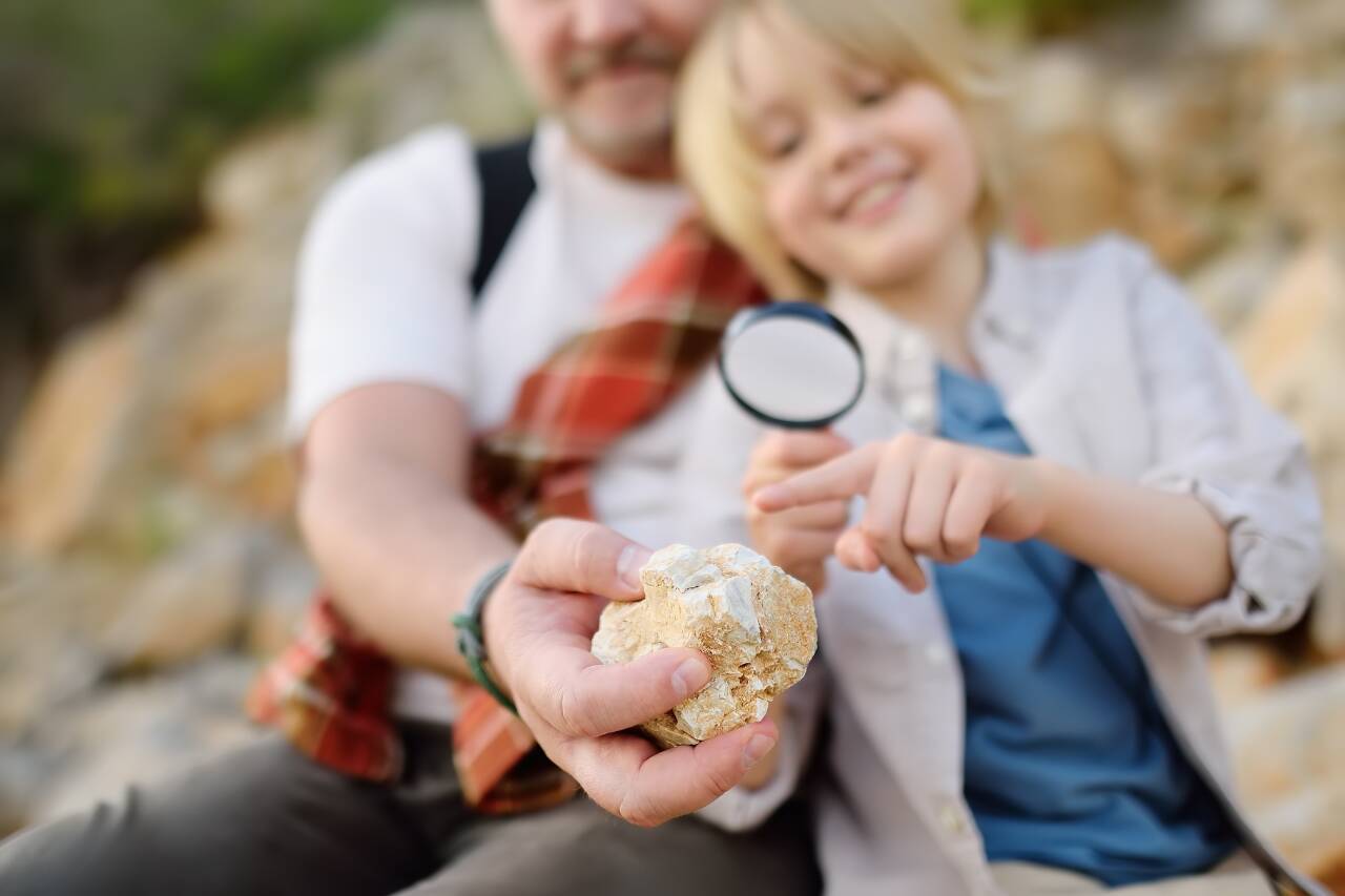 Pai e filho explorando pedras na natureza