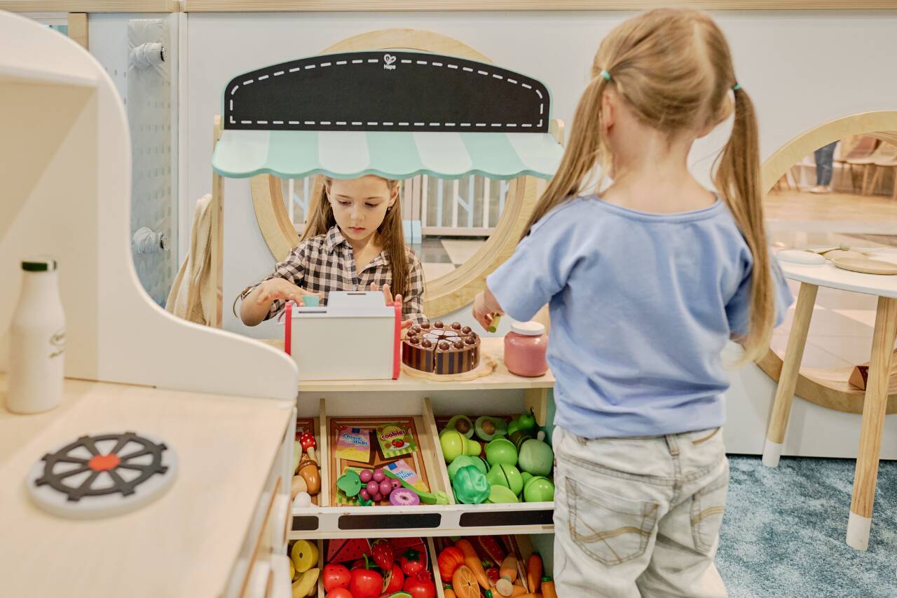 Crianças brincando de supermercado com frutas e guloseimas.