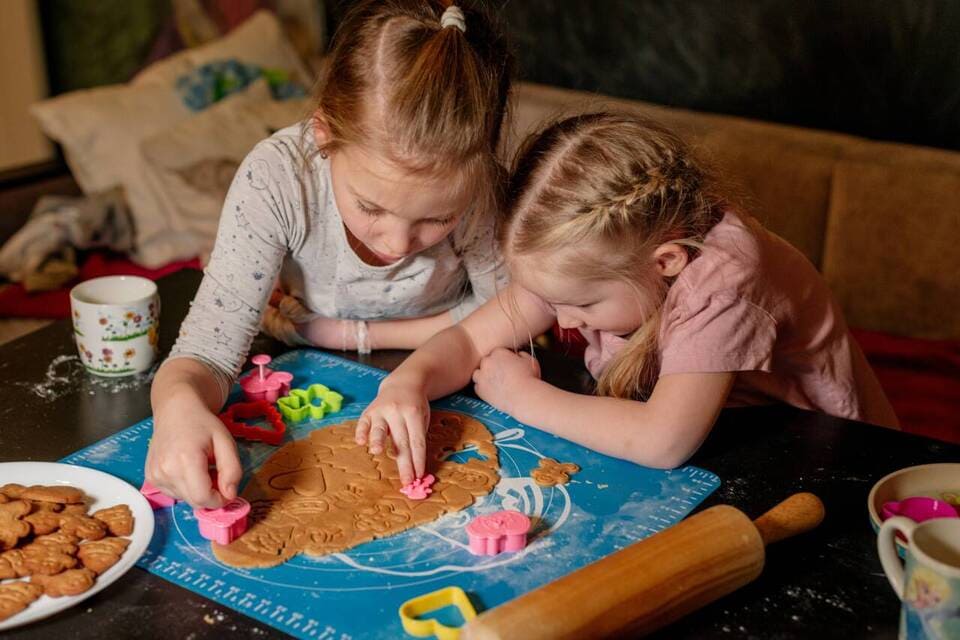 Duas meninas fazendo biscoitos de Natal na cozinha.