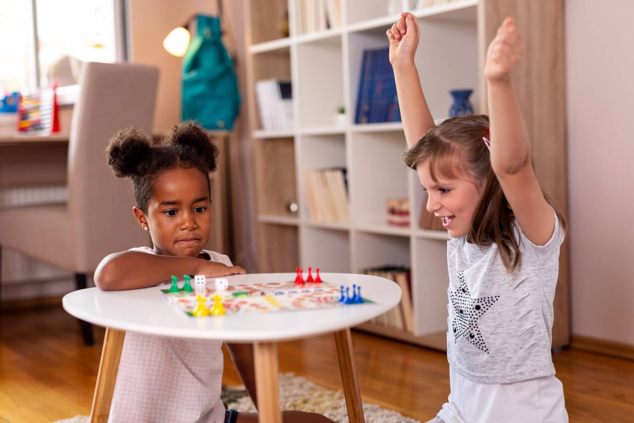 Duas meninas jogando um jogo de tabuleiro em casa.
