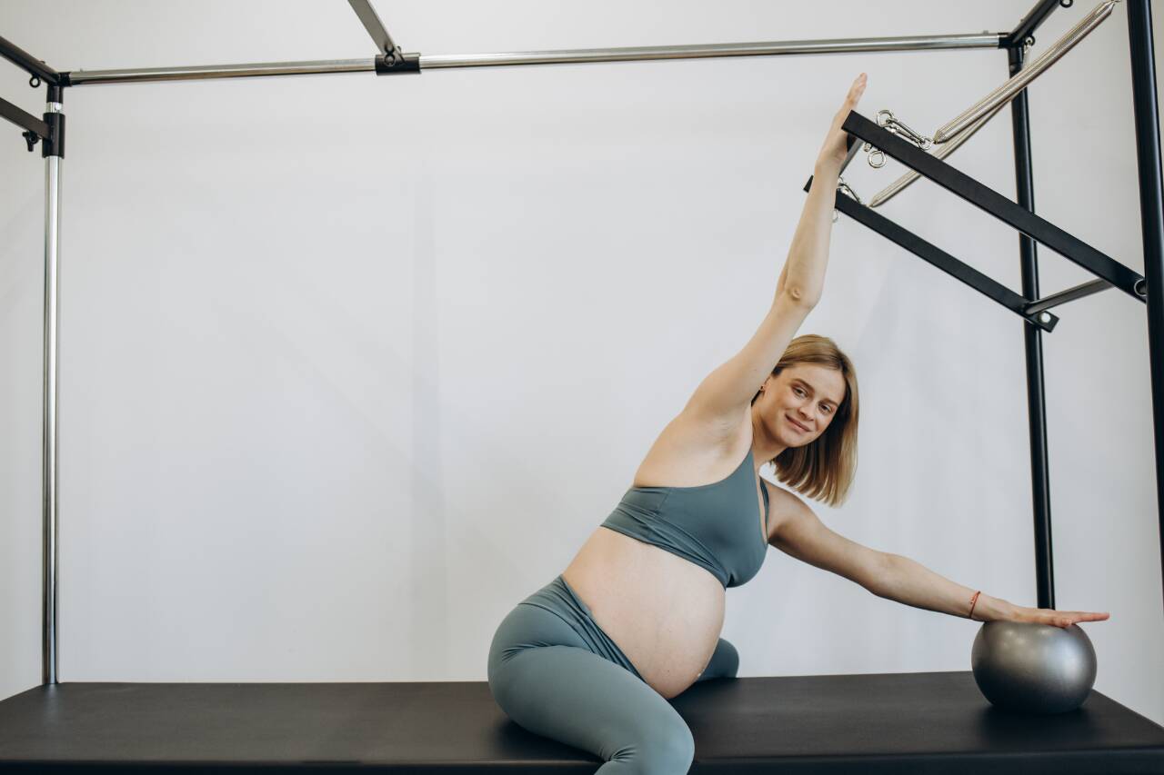 Mulher grávida se exercitando com bola