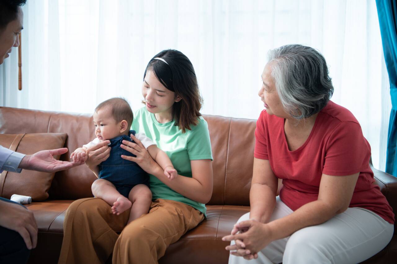 Mulheres e bebê em sofá conversando em casa