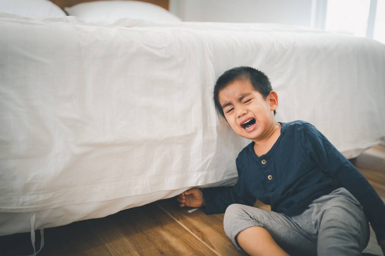Criança chorando ao lado da cama