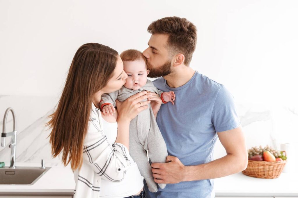 Pais sorrindo com bebê em ambiente acolhedor