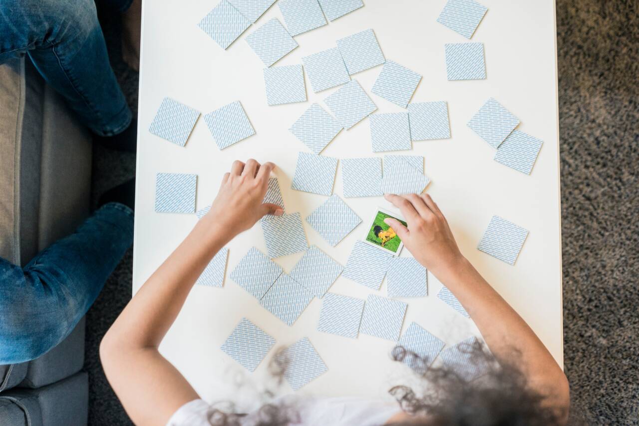 Pessoa jogando memória com cartas espalhadas