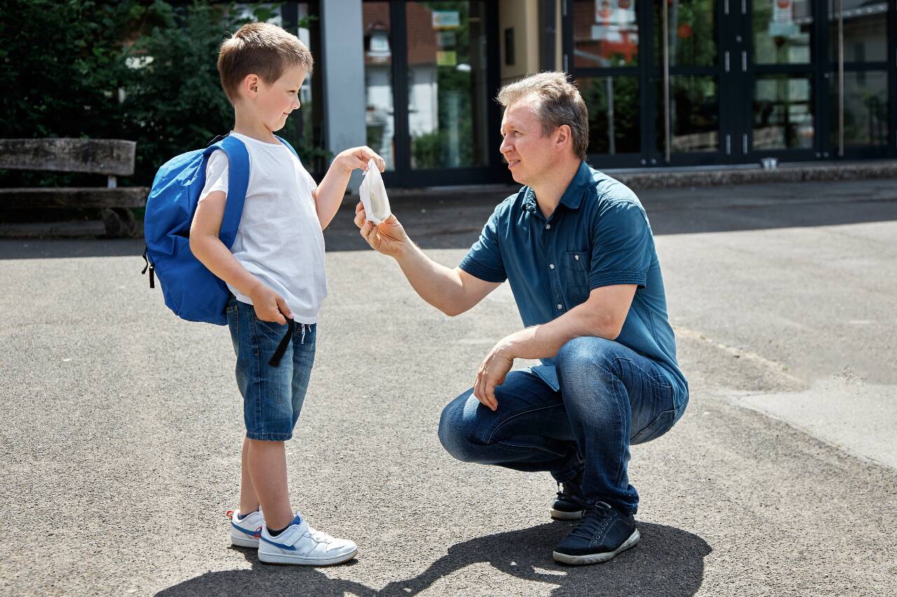 Pai entregando máscara para filho antes da escola
