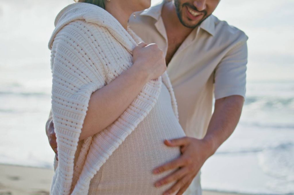 Casal feliz na praia esperando um bebê