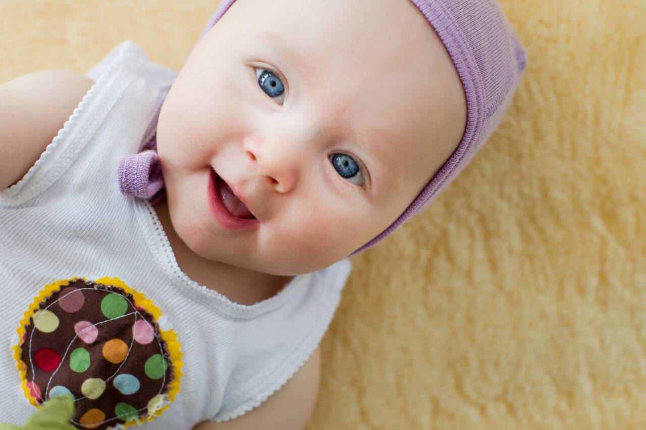 Bebê sorrindo com gorro e camiseta colorida
